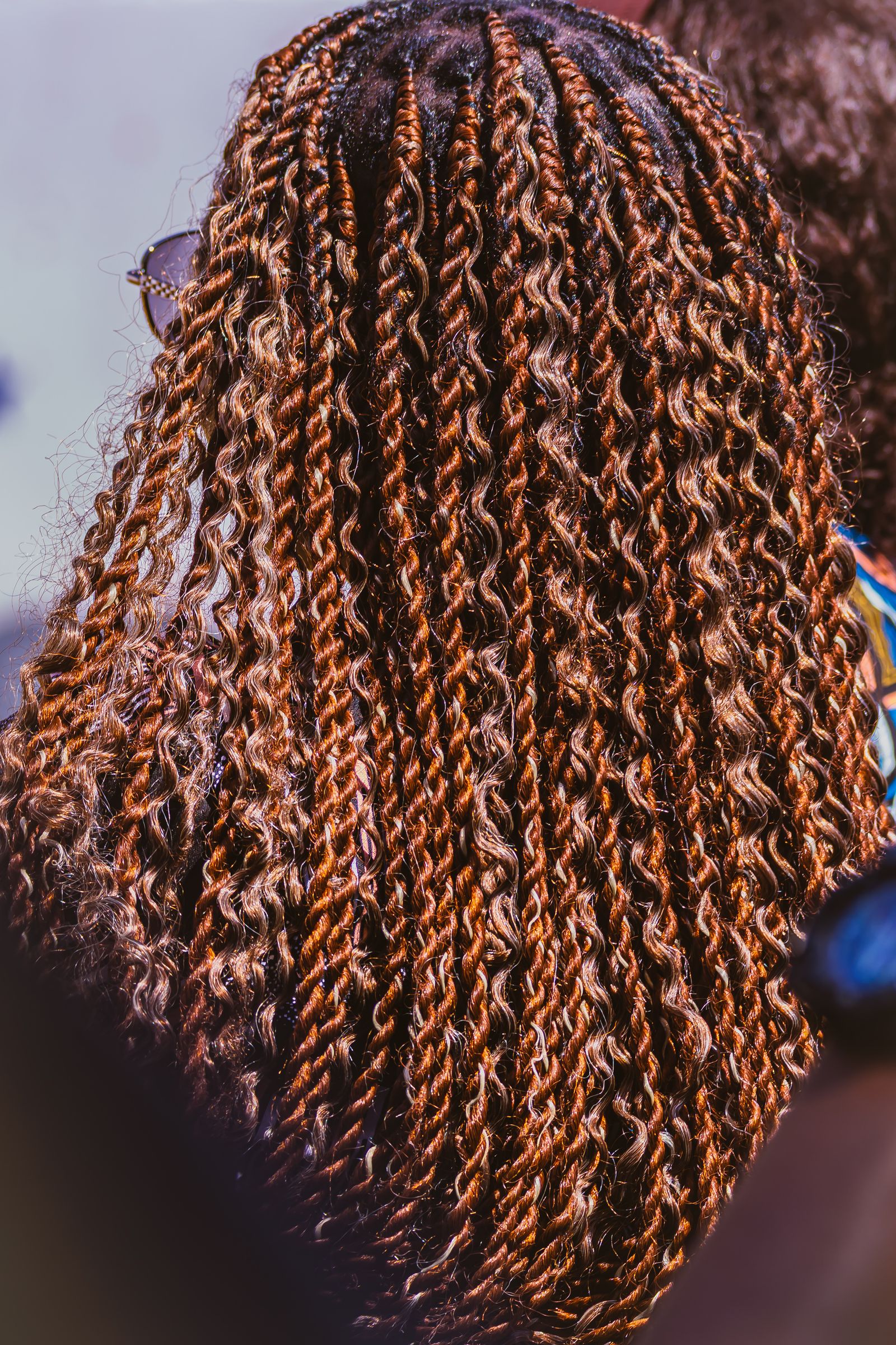 A stylist's hands parting and braiding natural hair